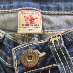 Close-up of brand label and button on denim shorts.
