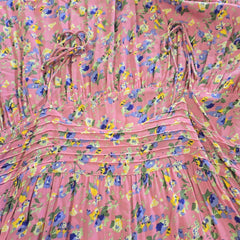 Pink floral dress with a tie shoulder straps on a matching pink background