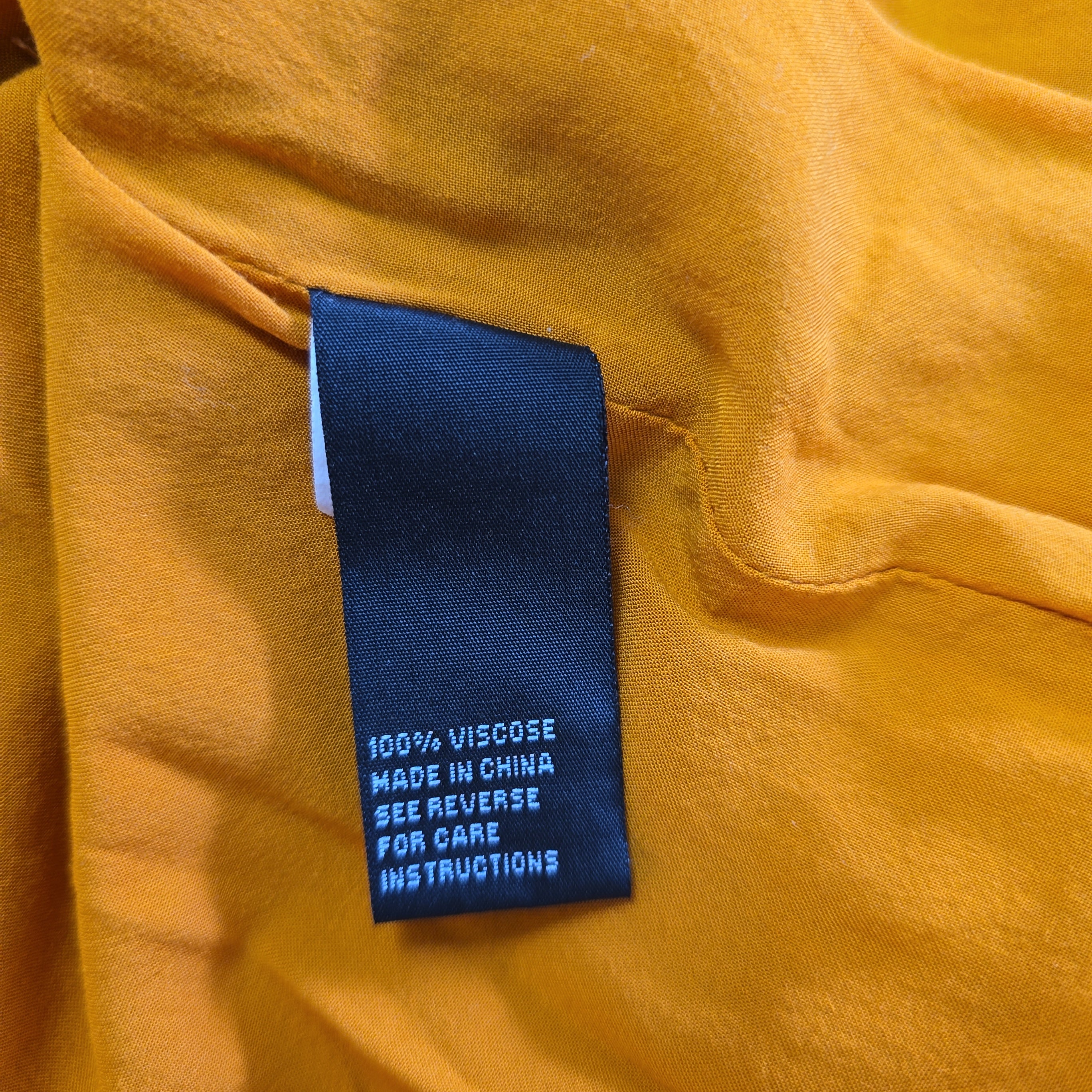 Close-up of a label on a yellow fabric garment with text.