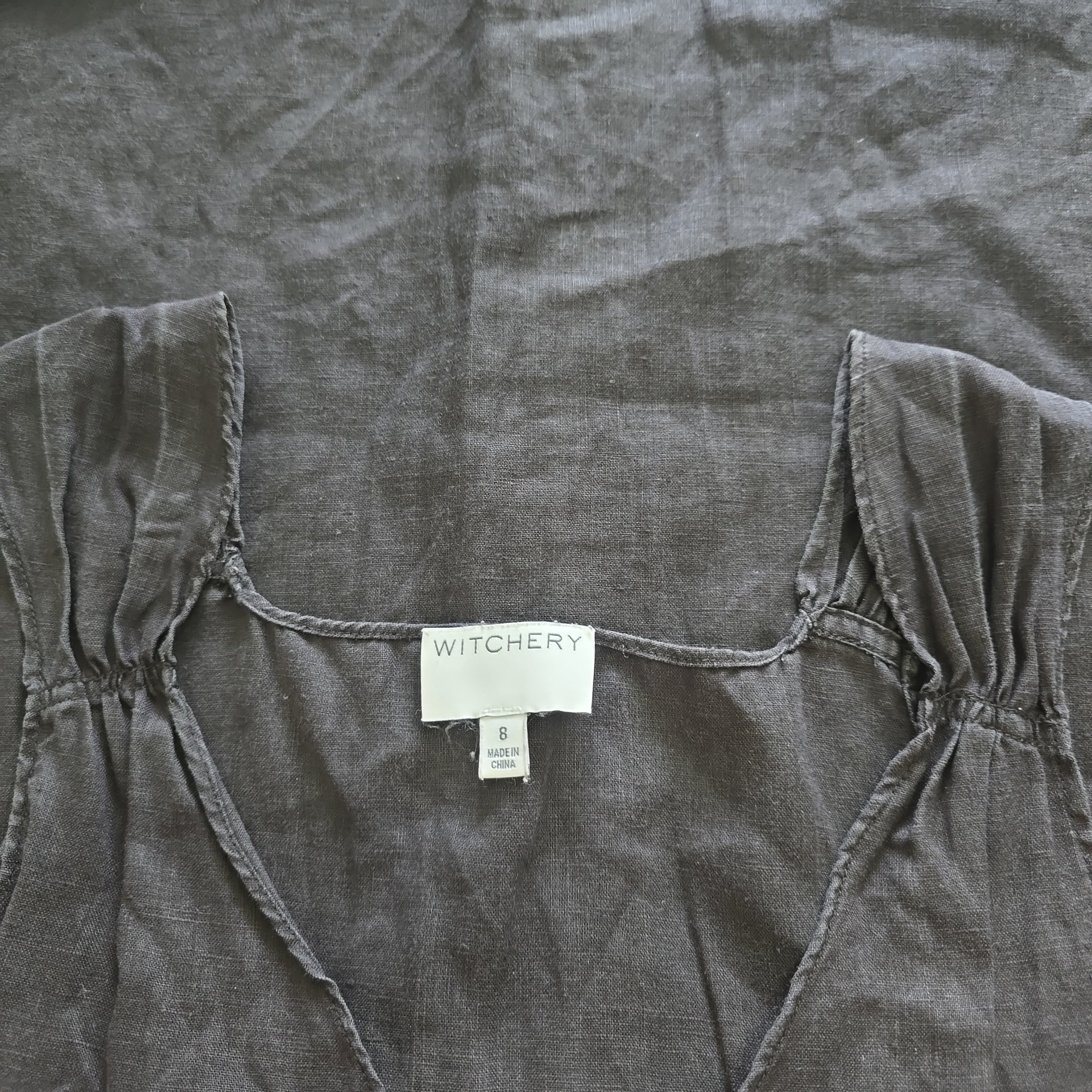 Dark gray top with a visible brand label on a matching fabric background