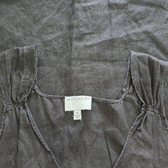 Dark gray top with a visible brand label on a matching fabric background