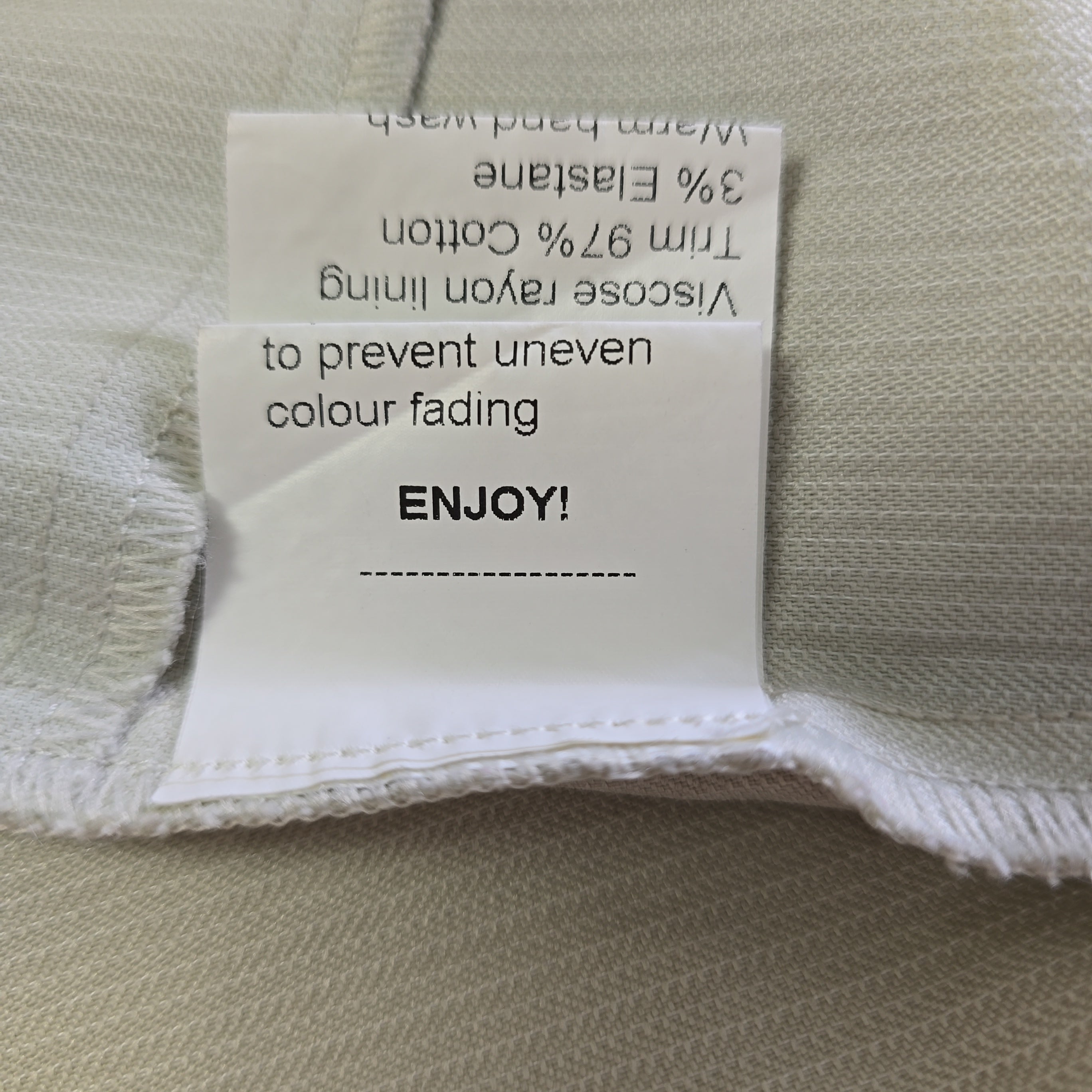 Fabric tag with material information and care instructions on a beige fabric background