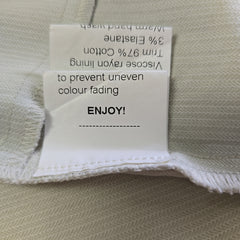 Fabric tag with material information and care instructions on a beige fabric background