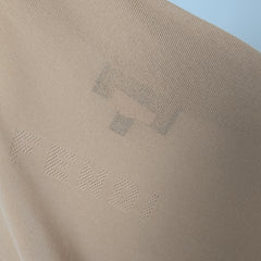 Close-up of beige fabric with a subtle pattern on a light blue background