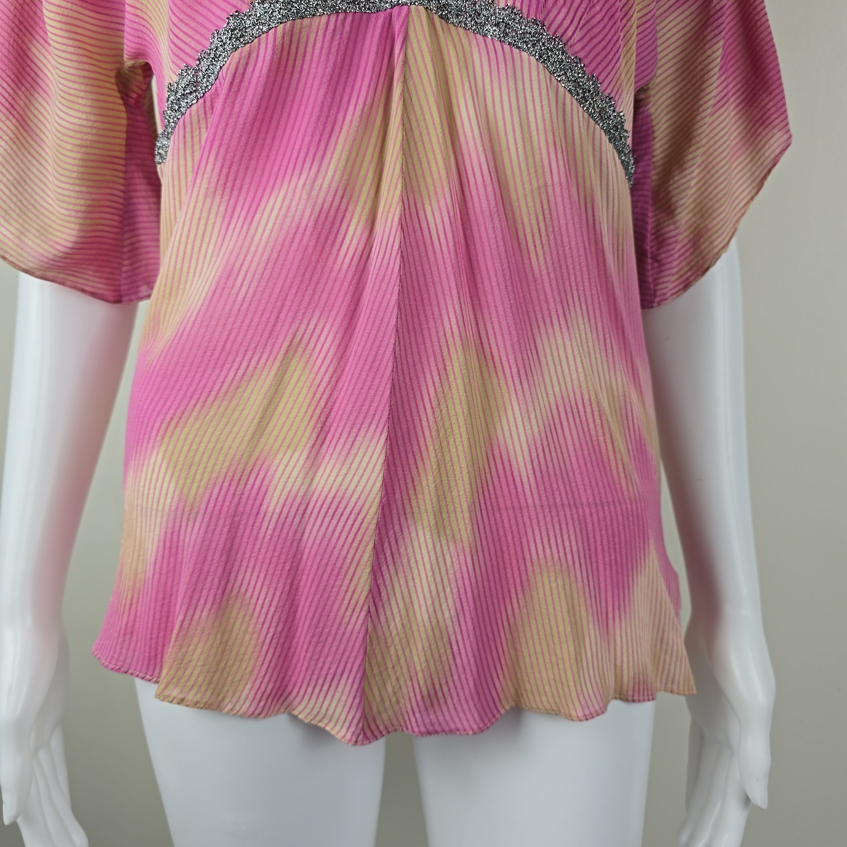 Pink and beige top with silver trim on a white mannequin against a neutral background