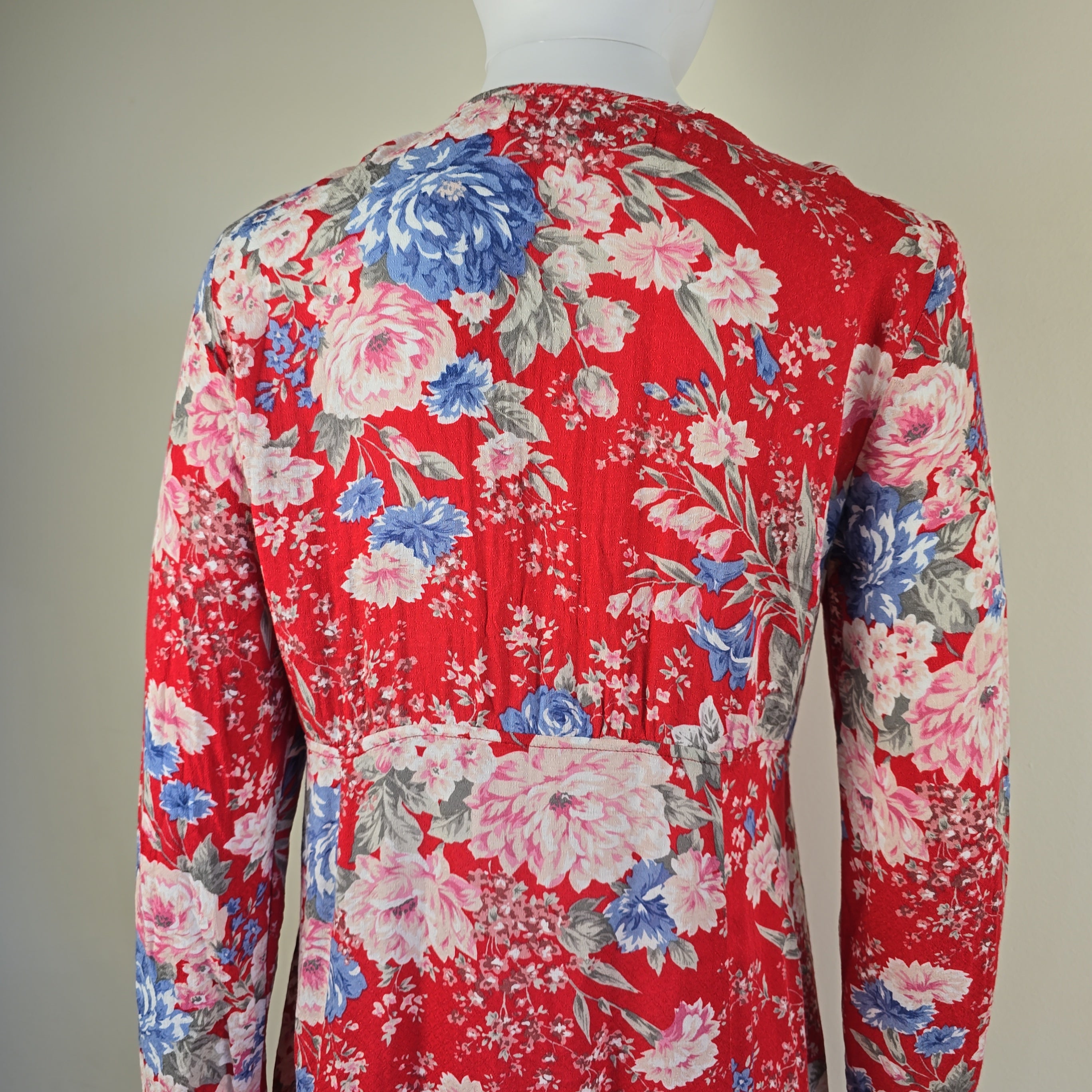 Red floral fabric with pink and blue flowers on a plain background