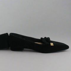 Black flat shoe with a bow on a tiled floor