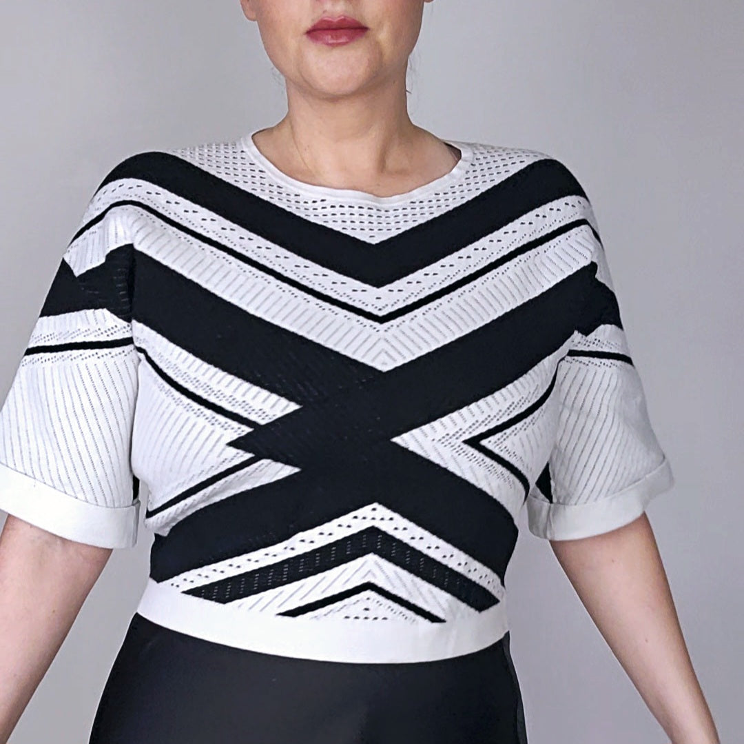 A model wearing a Karen Millen black and white knit top with a chevron design and cuffed short sleeves.