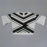 White sweater with black geometric patterns on a tiled floor