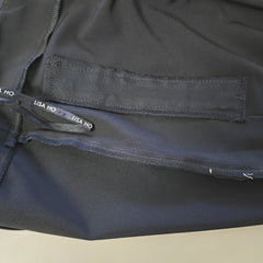Close-up of a black pants with a visible brand label on a beige background
