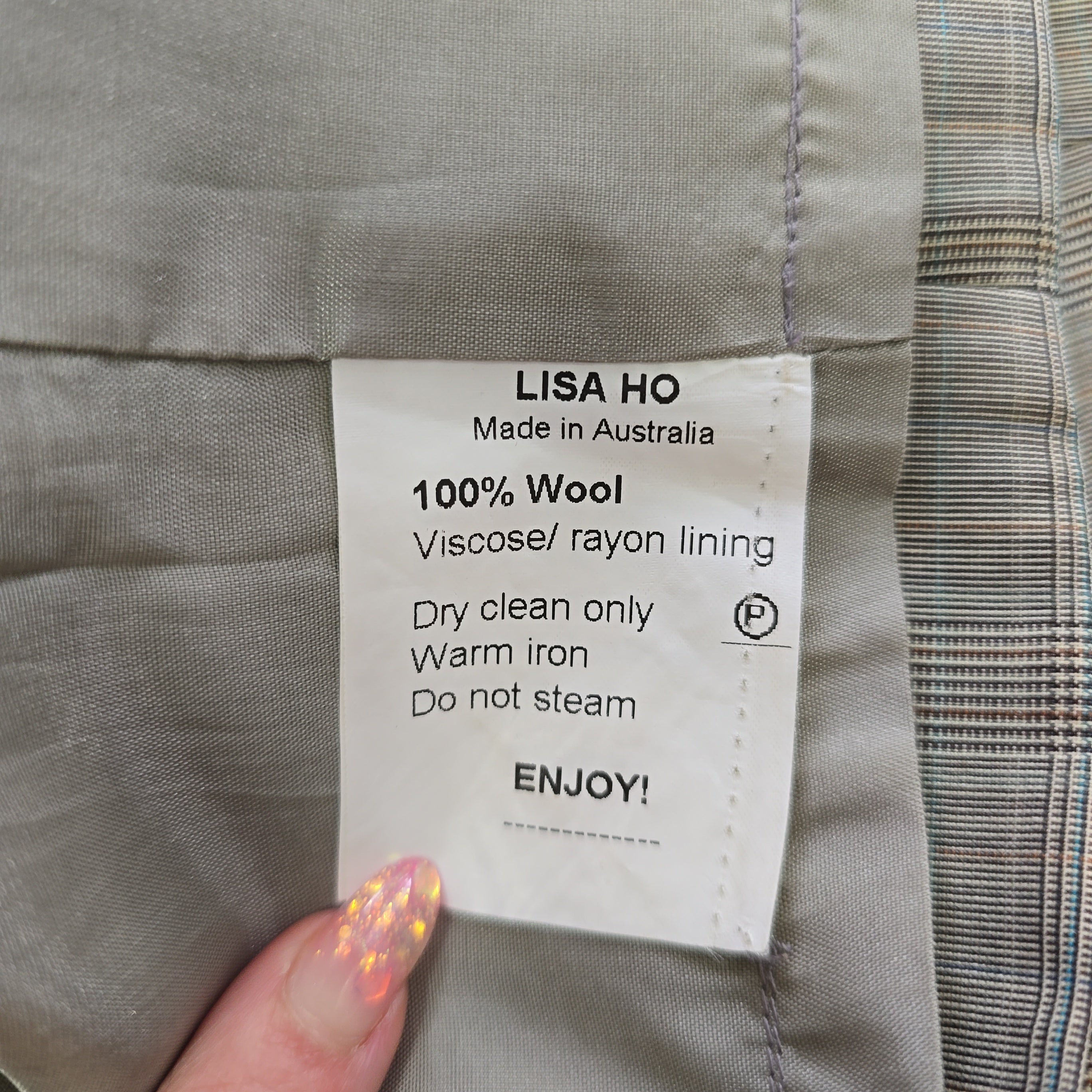 Label on a piece of clothing with text and a hand holding it.