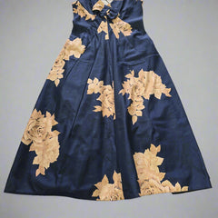 Blue dress with beige floral embroidery on a tiled floor.