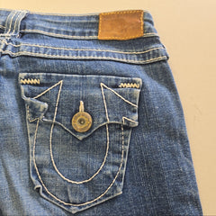 Close-up of a blue denim pocket with a button on a beige background