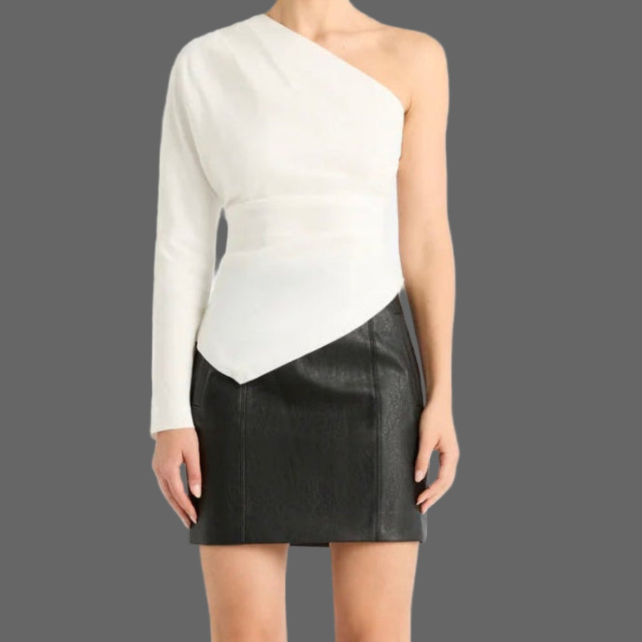 Woman wearing a one-shoulder white top and black skirt with knee-high black boots on a white background