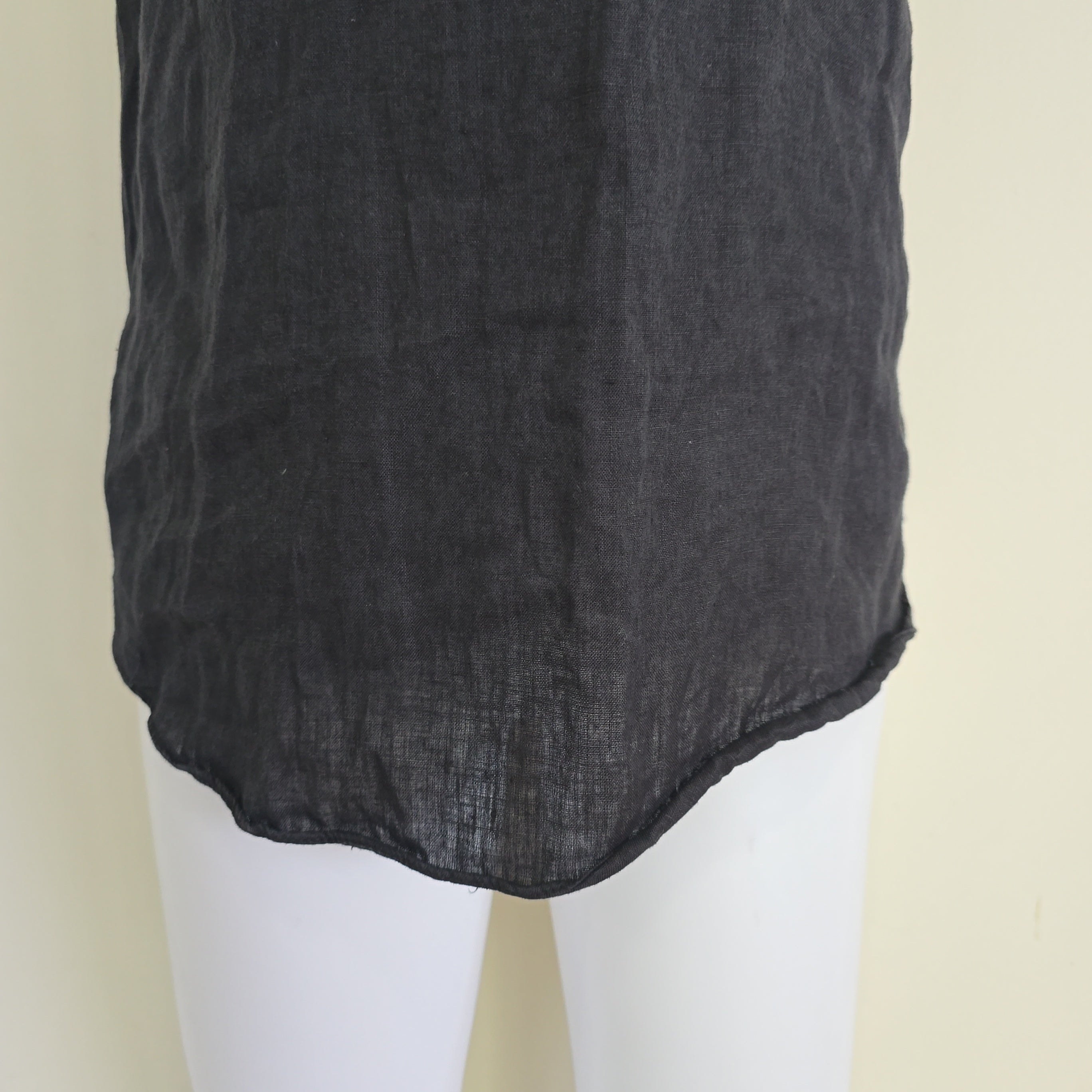 Black fabric draped over a white mannequin on a beige background