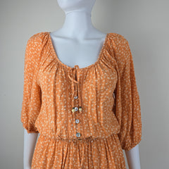Orange dress with white pattern on a mannequin against a gray background
