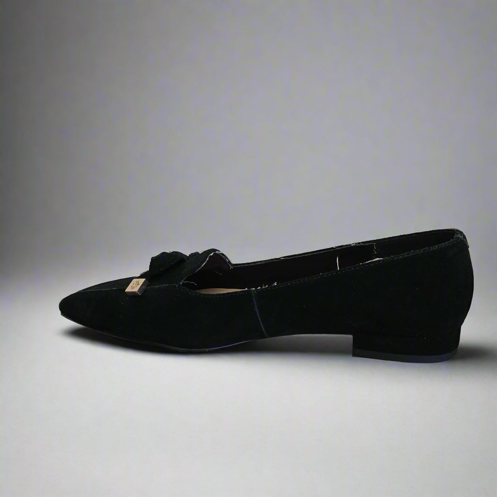 Black shoe with a bow on a white floor