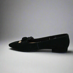 Black shoe with a bow on a white floor