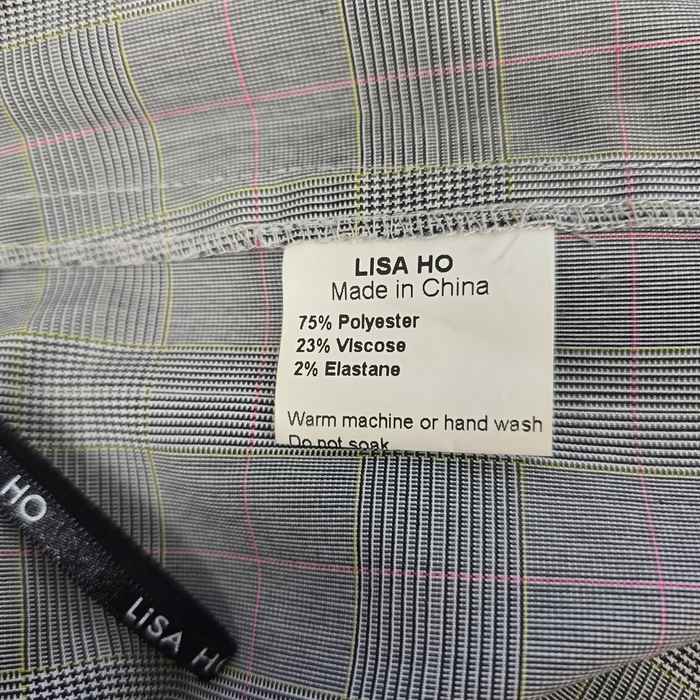 Close-up of a label on a gray checkered fabric with 'Lisa Ho' branding.