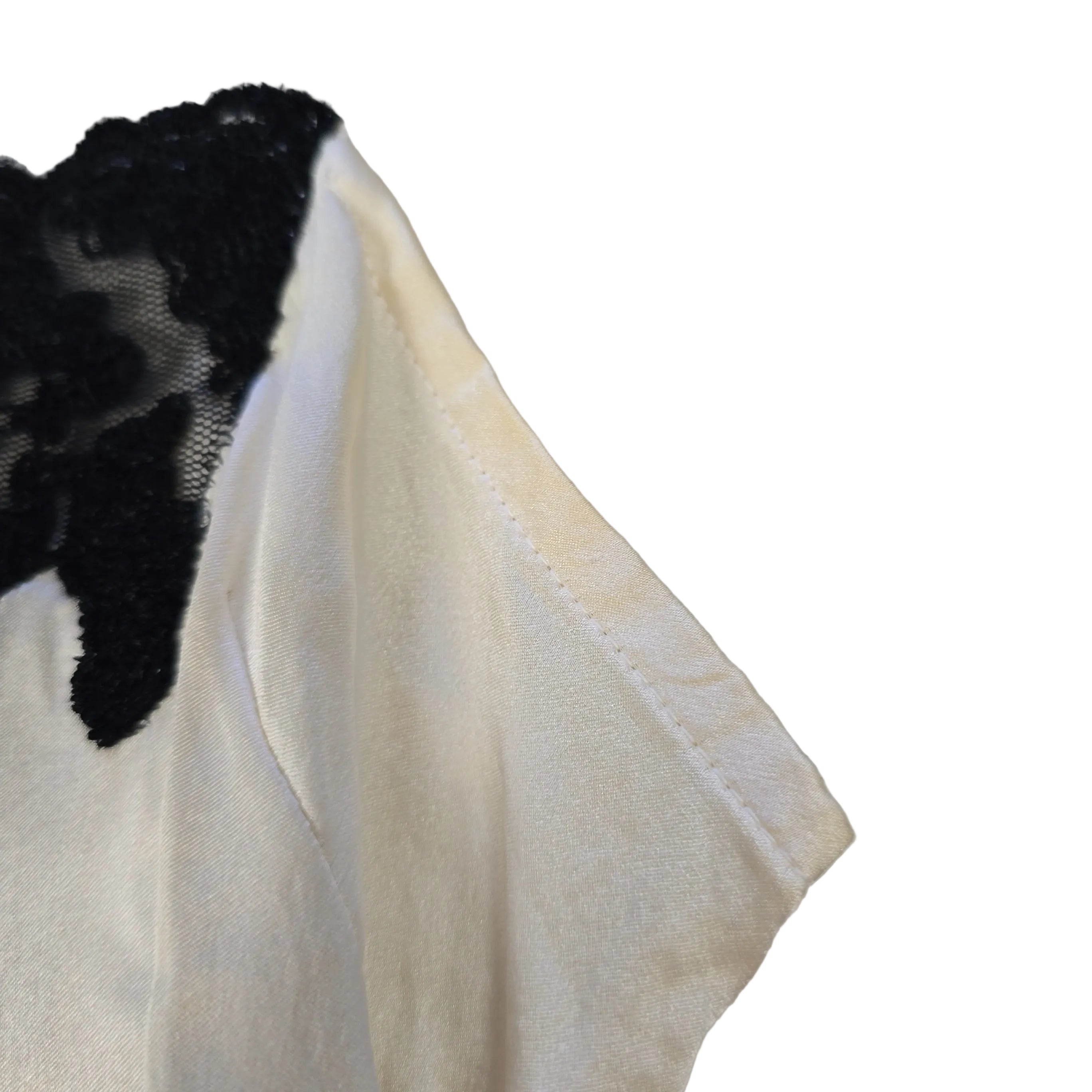 Close-up of a white fabric with black lace trim on a light gray background