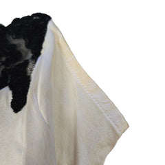 Close-up of a white fabric with black lace trim on a light gray background