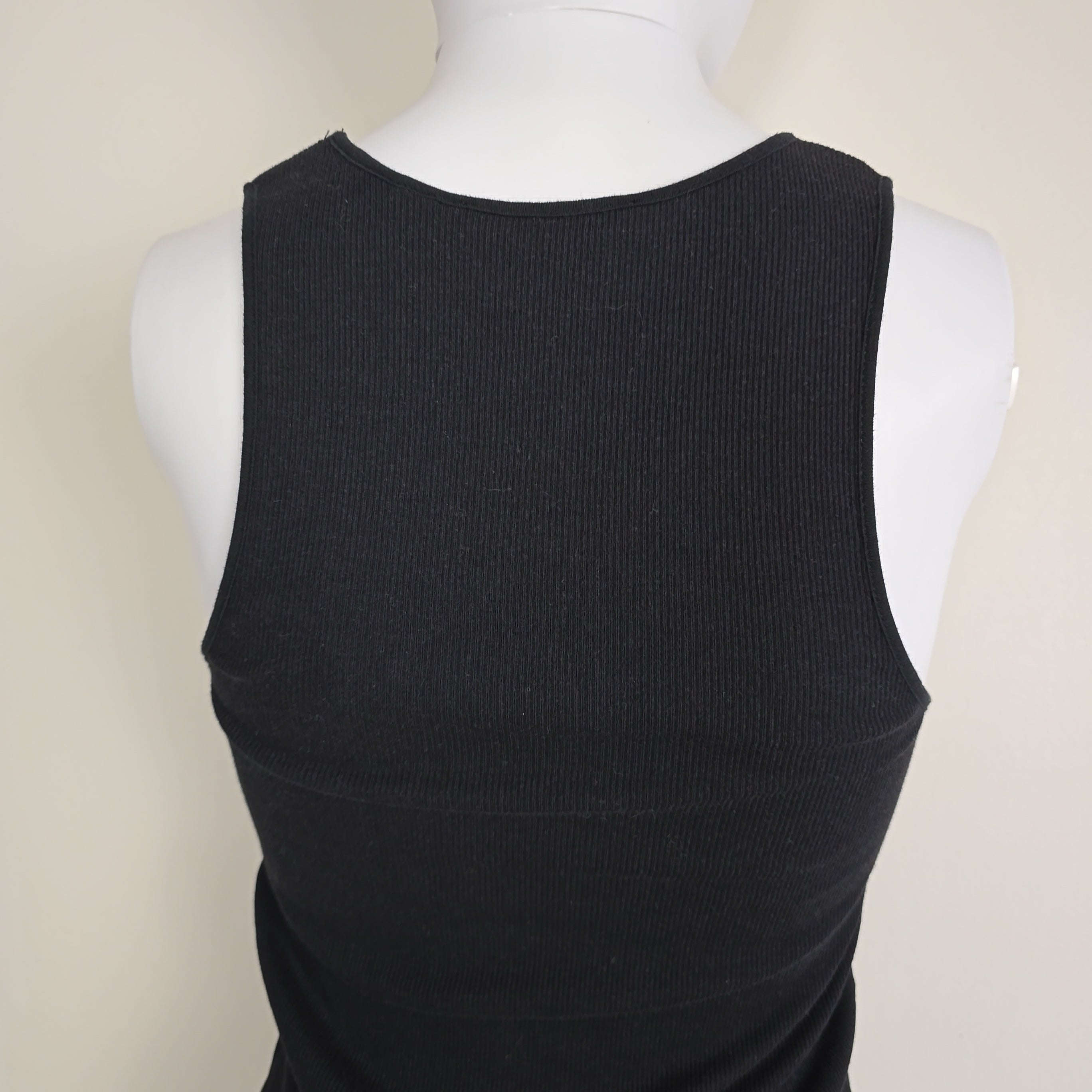 Black sleeveless top on a mannequin against a beige background