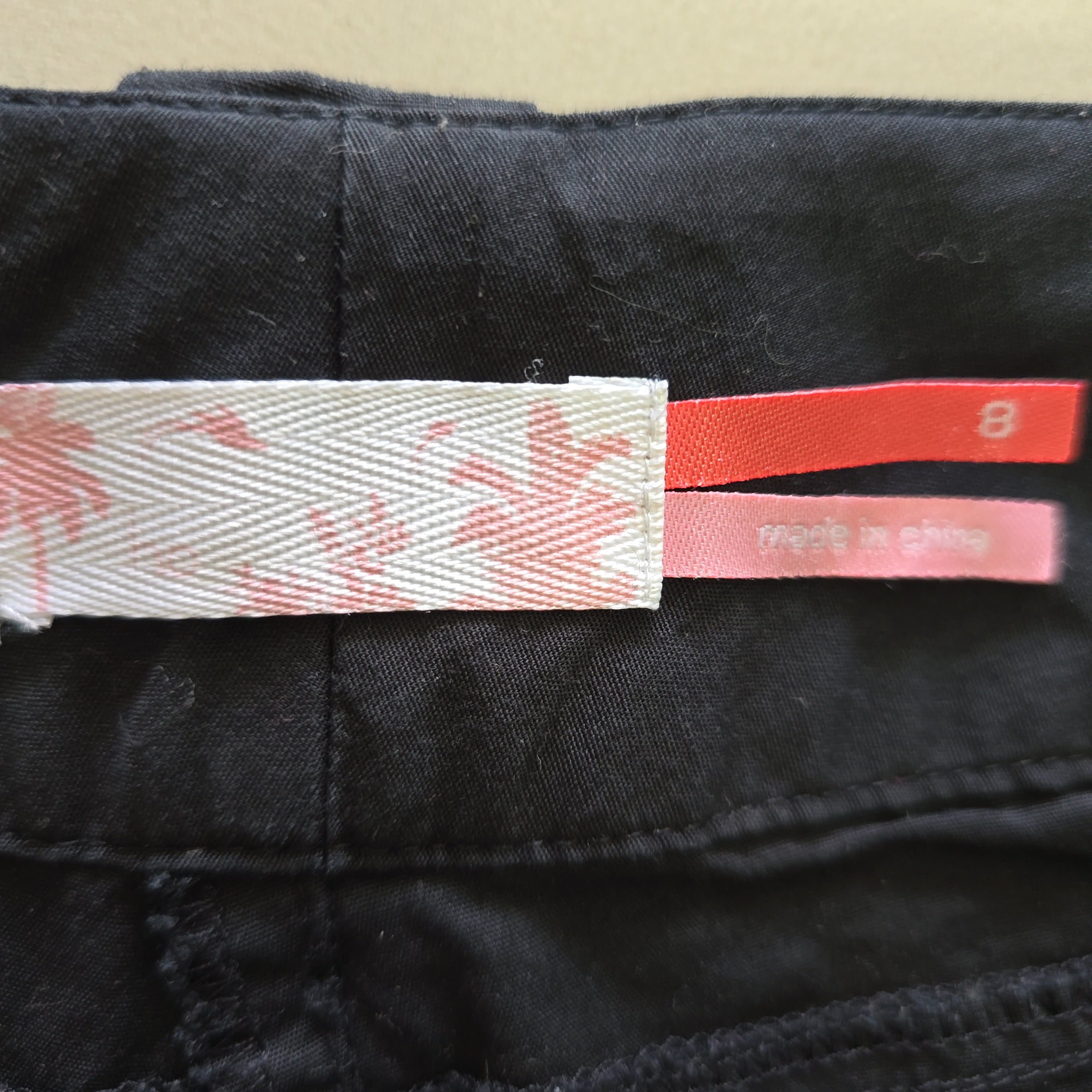 Close-up of a black garment with a pink and white tag featuring a star pattern.