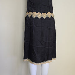 Black skirt with gold lace trim on a white mannequin against a beige background