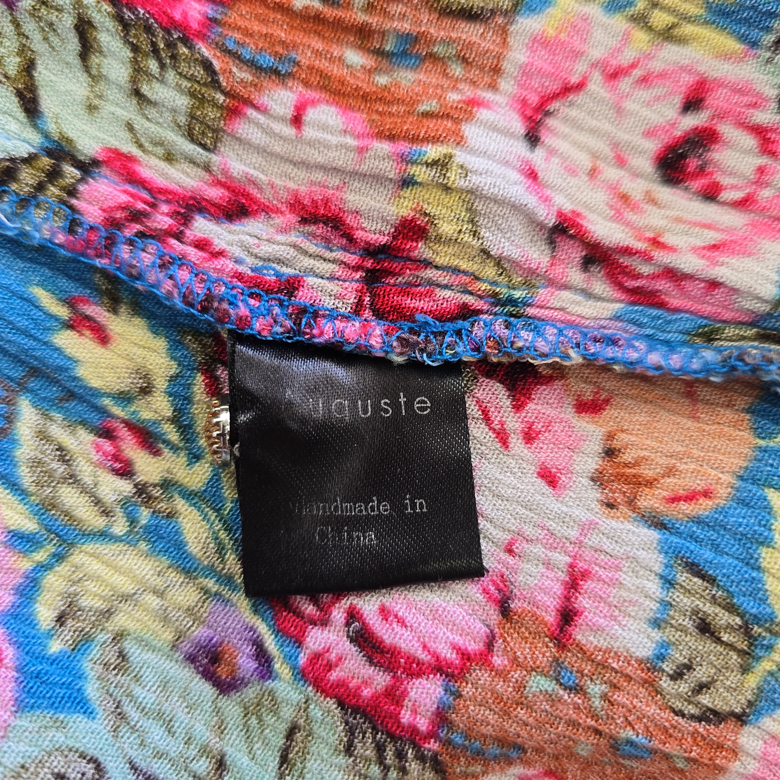 Close-up of a colorful fabric with a brand tag on a floral patterned background