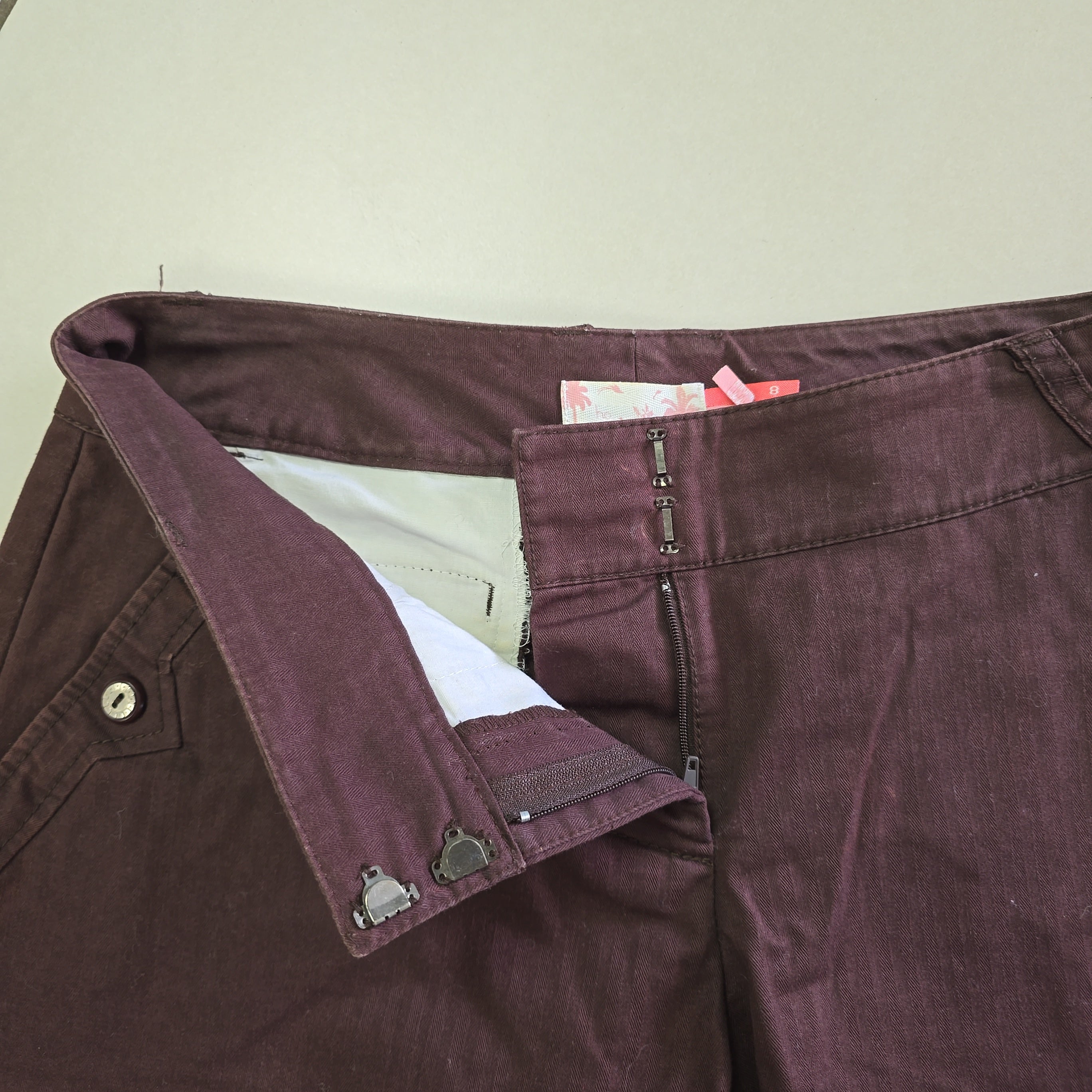Close-up of a maroon shorts with a beige interior lining on a light background