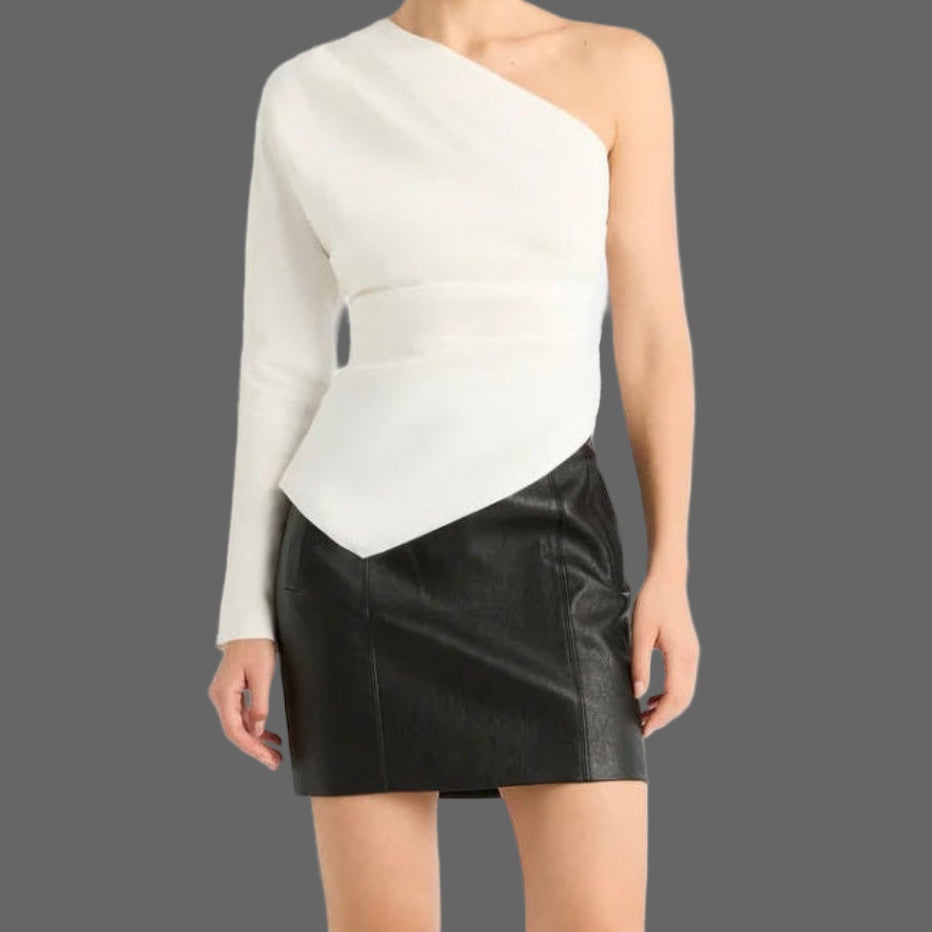 Woman wearing a white one-shoulder top and black skirt with knee-high black boots on a white background