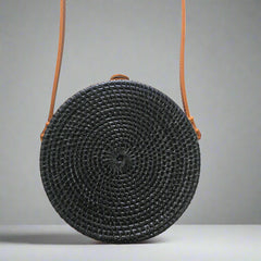 Black woven handbag with an orange strap on a tiled floor