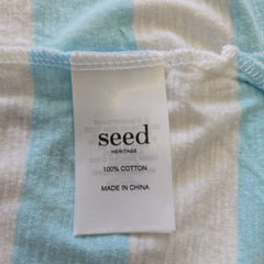 Close-up of a fabric with a 'seed' label on a blue and beige striped background