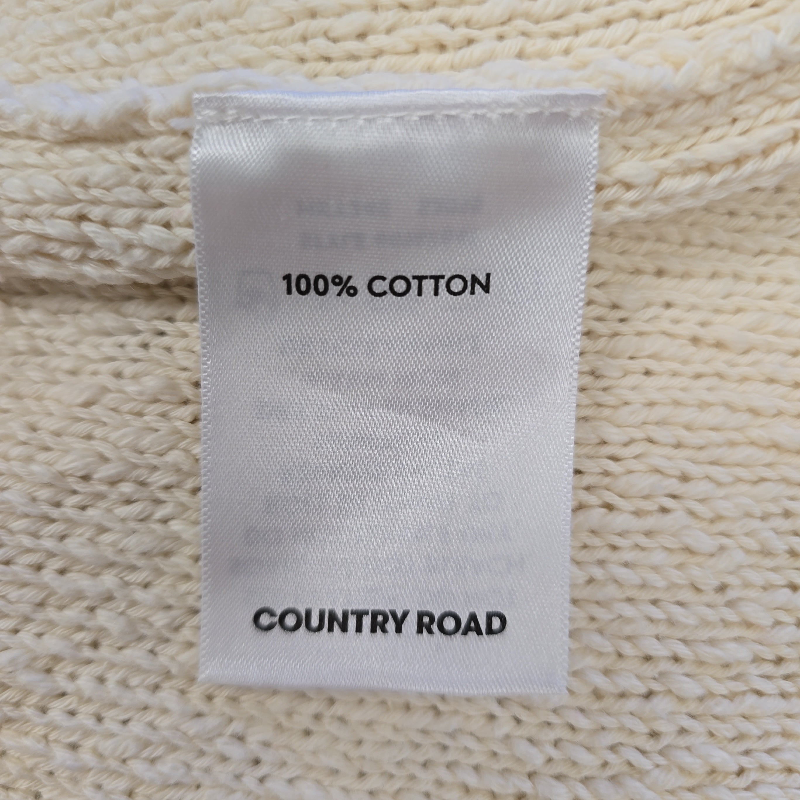 Label on a textured fabric surface indicating 100% cotton and 'Country Road' brand.