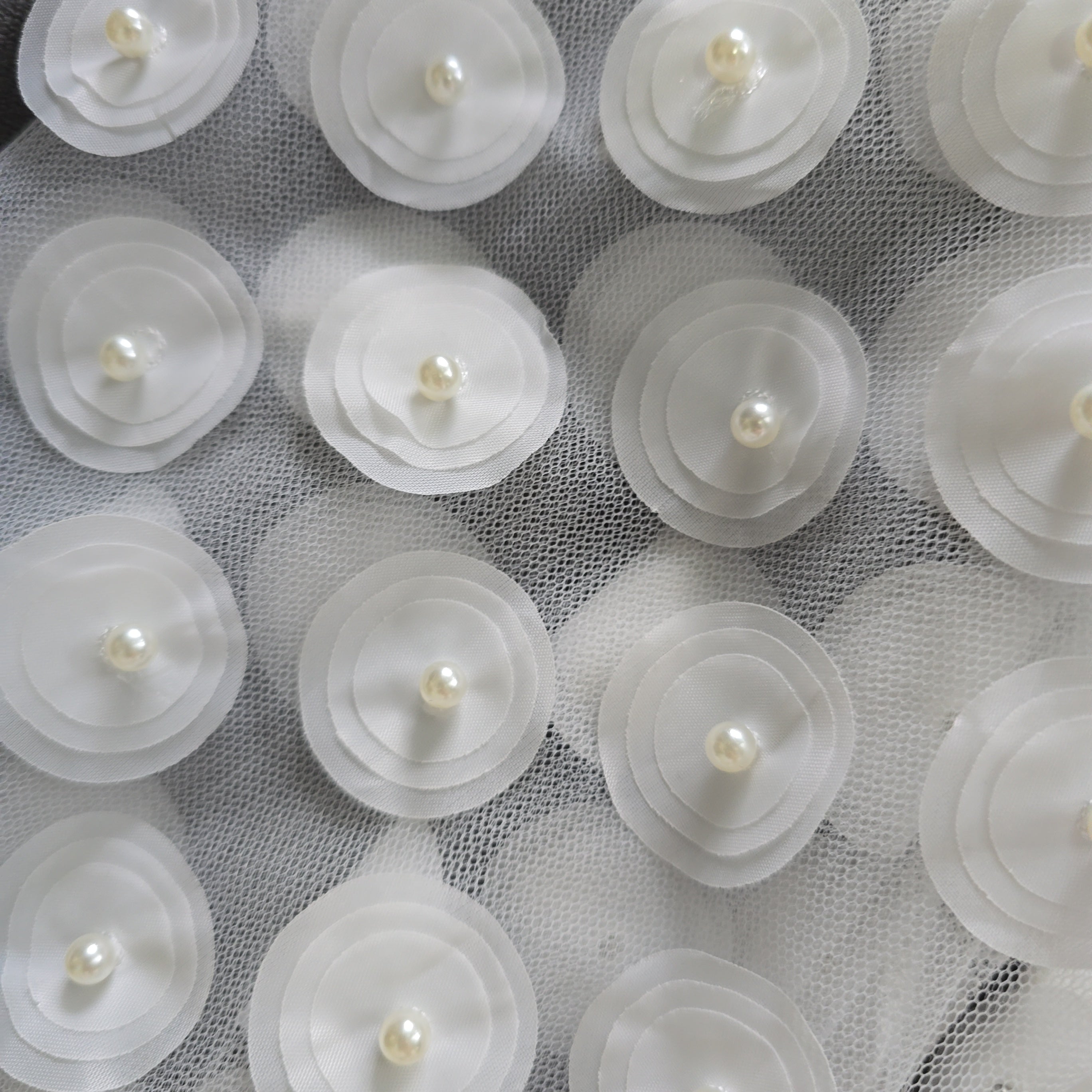White floral decorations with pearls on a textured white background