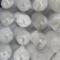 White floral decorations with pearls on a textured white background