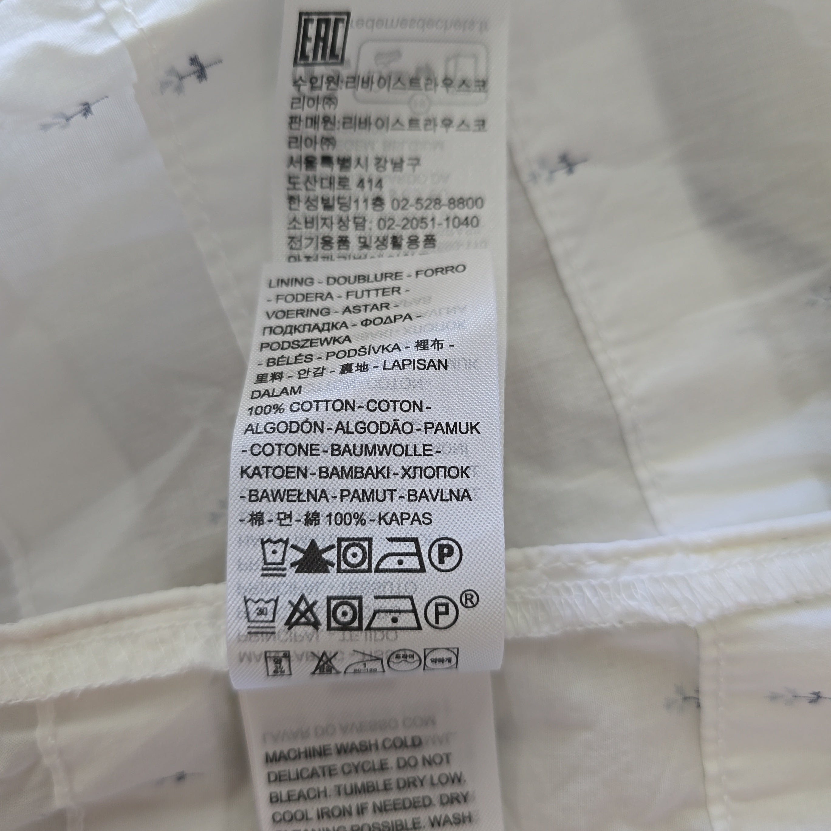 Clothing label on a white dress with text and symbols