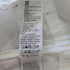 Clothing label on a white dress with text and symbols