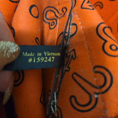 Close-up of an orange fabric with black patterns and a visible 'Made in Vietnam' tag.