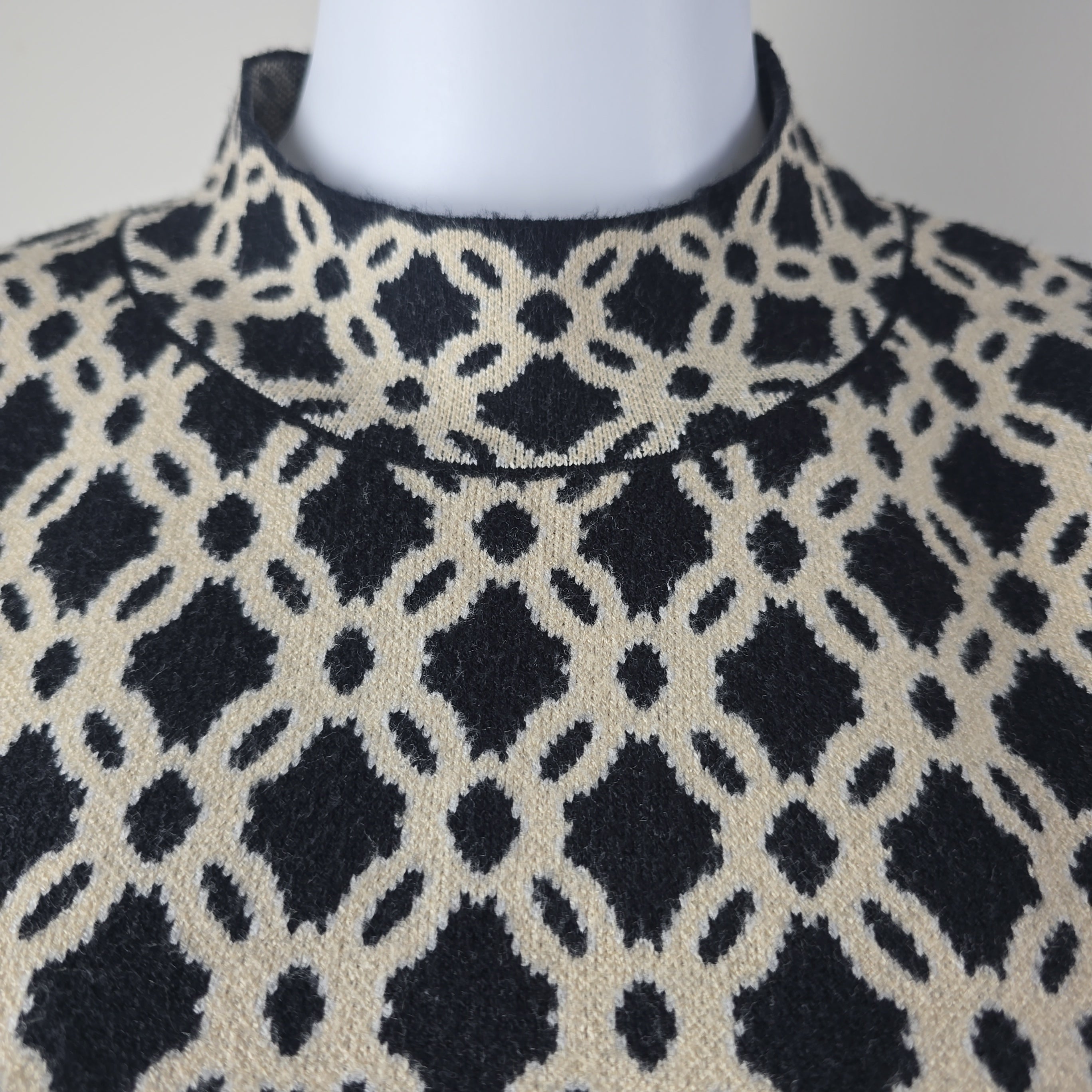 Close-up of a patterned fabric with black and beige design on a mannequin.
