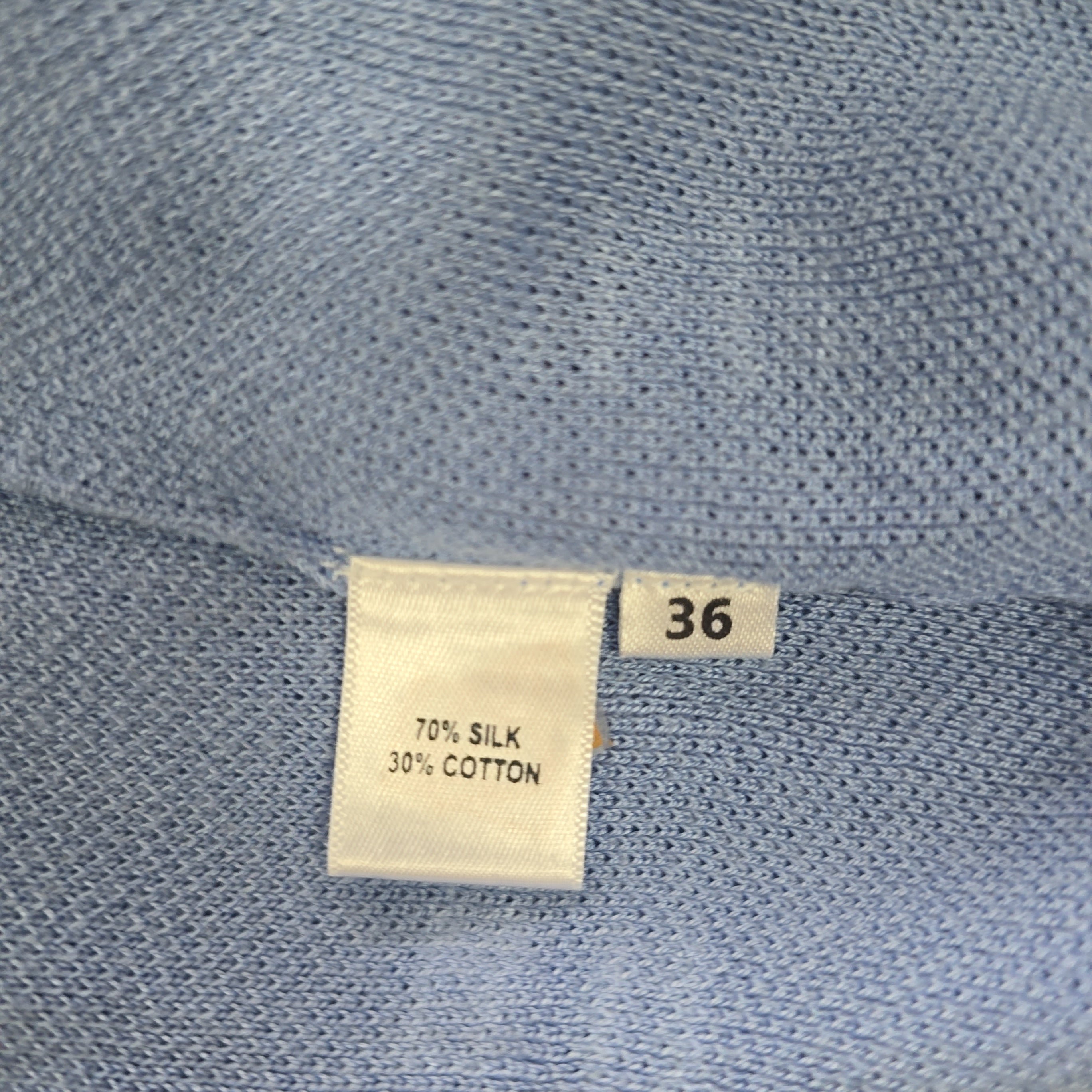 Close-up of a blue fabric with a size label and fabric composition tag.