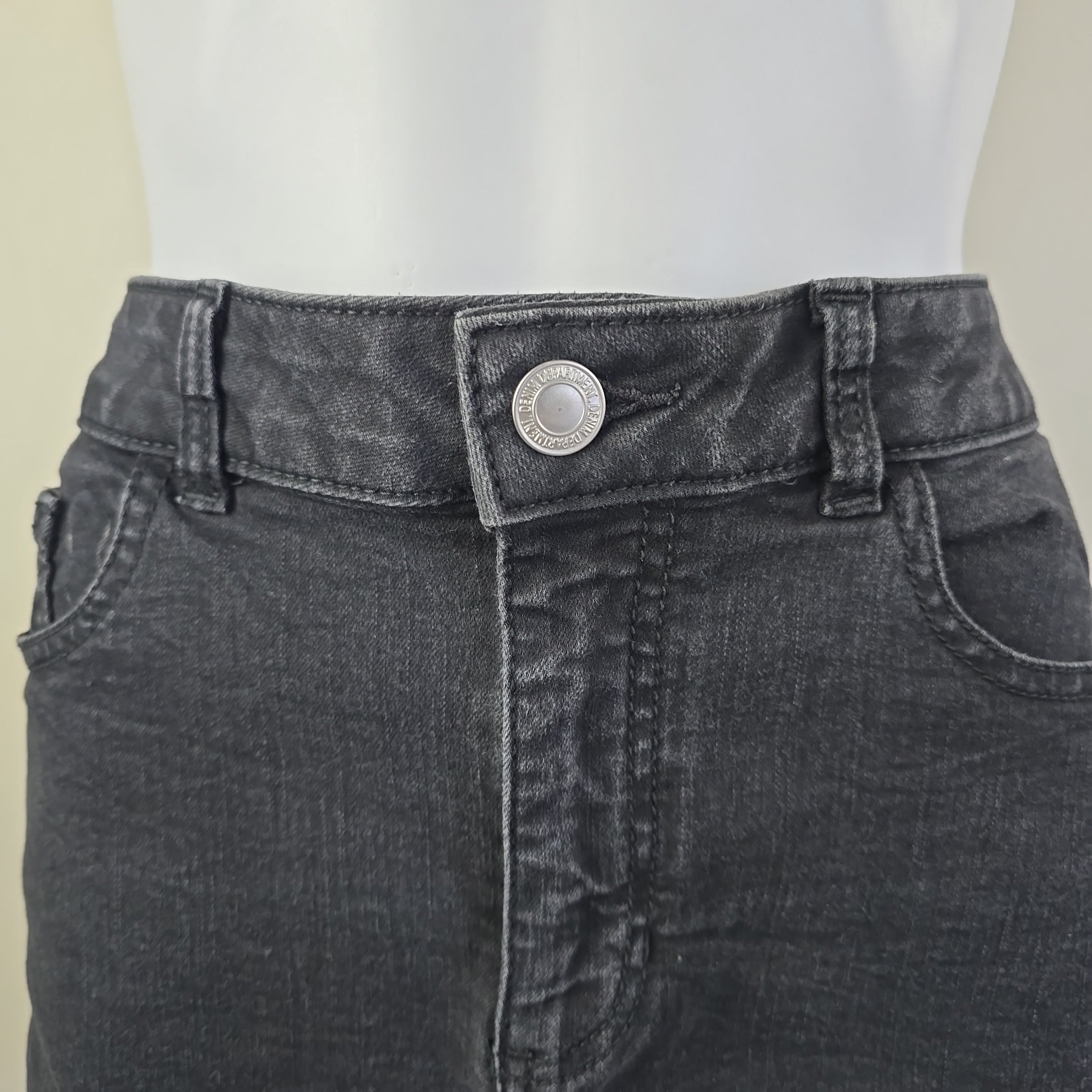 Close-up of a gray denim skirt with a button on a white background
