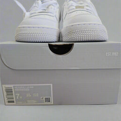 White sneakers with a gray box on a light-colored floor.
