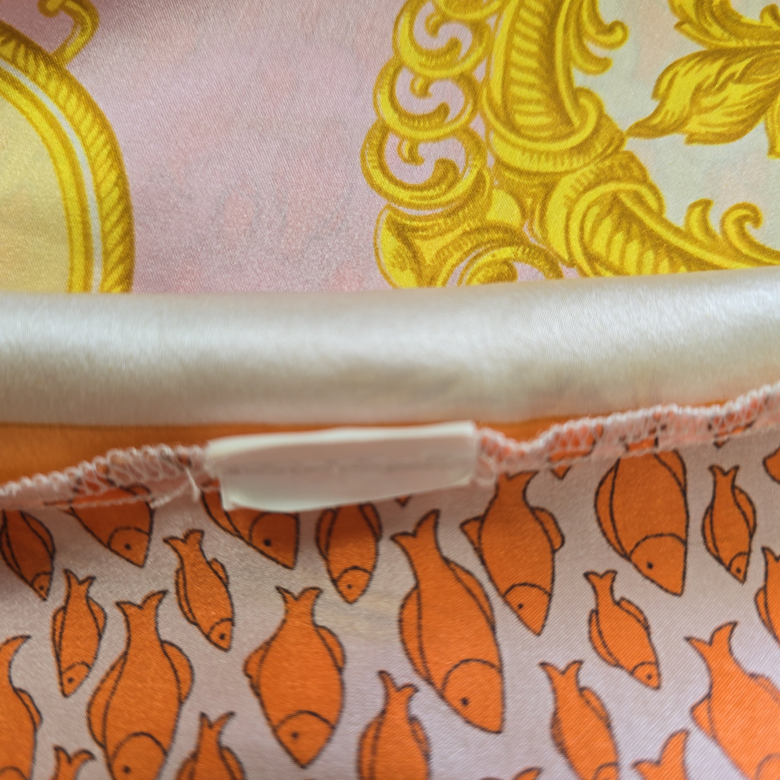 Close-up of fabric with yellow floral pattern and orange fish pattern.