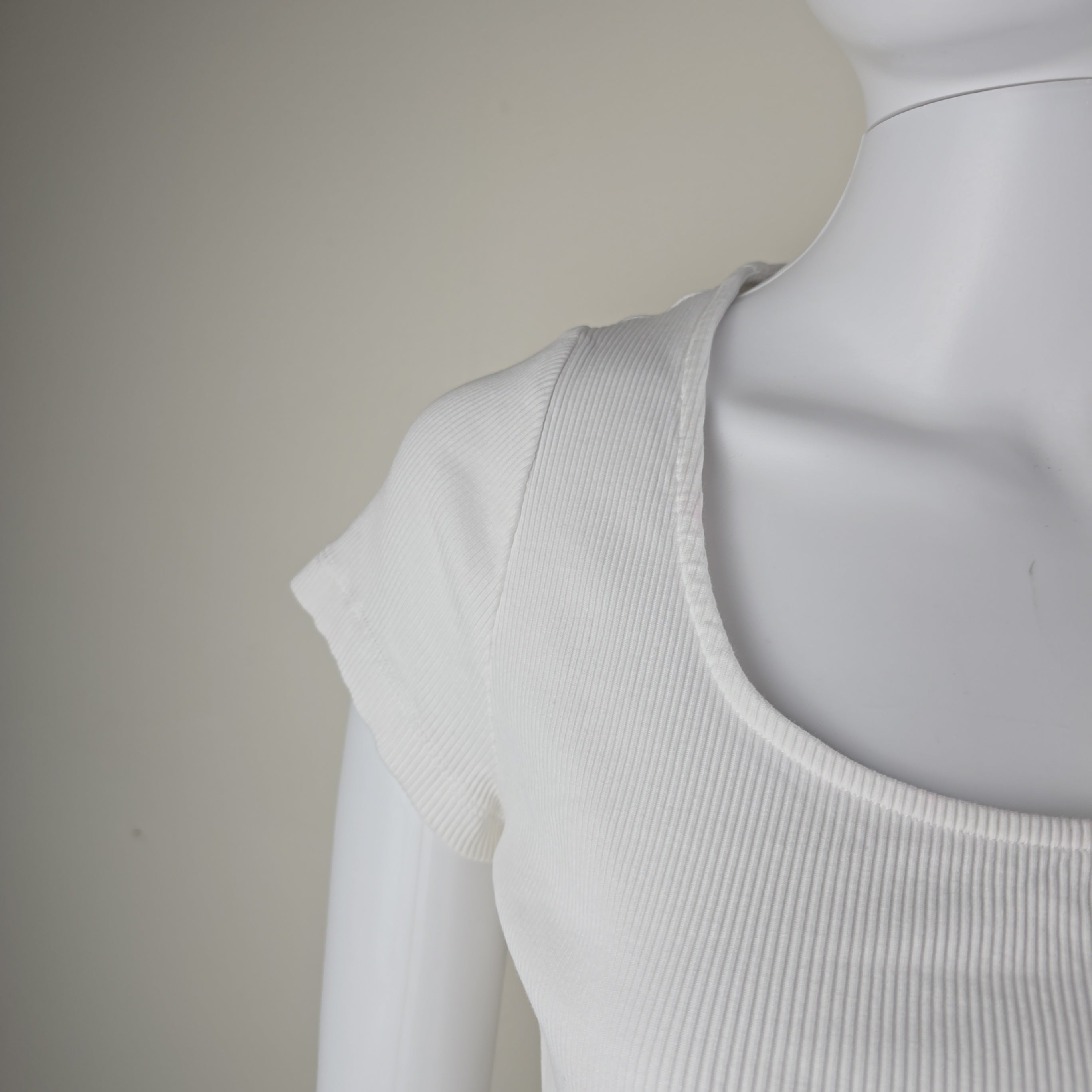 Close-up of a white sleeveless top on a light gray background