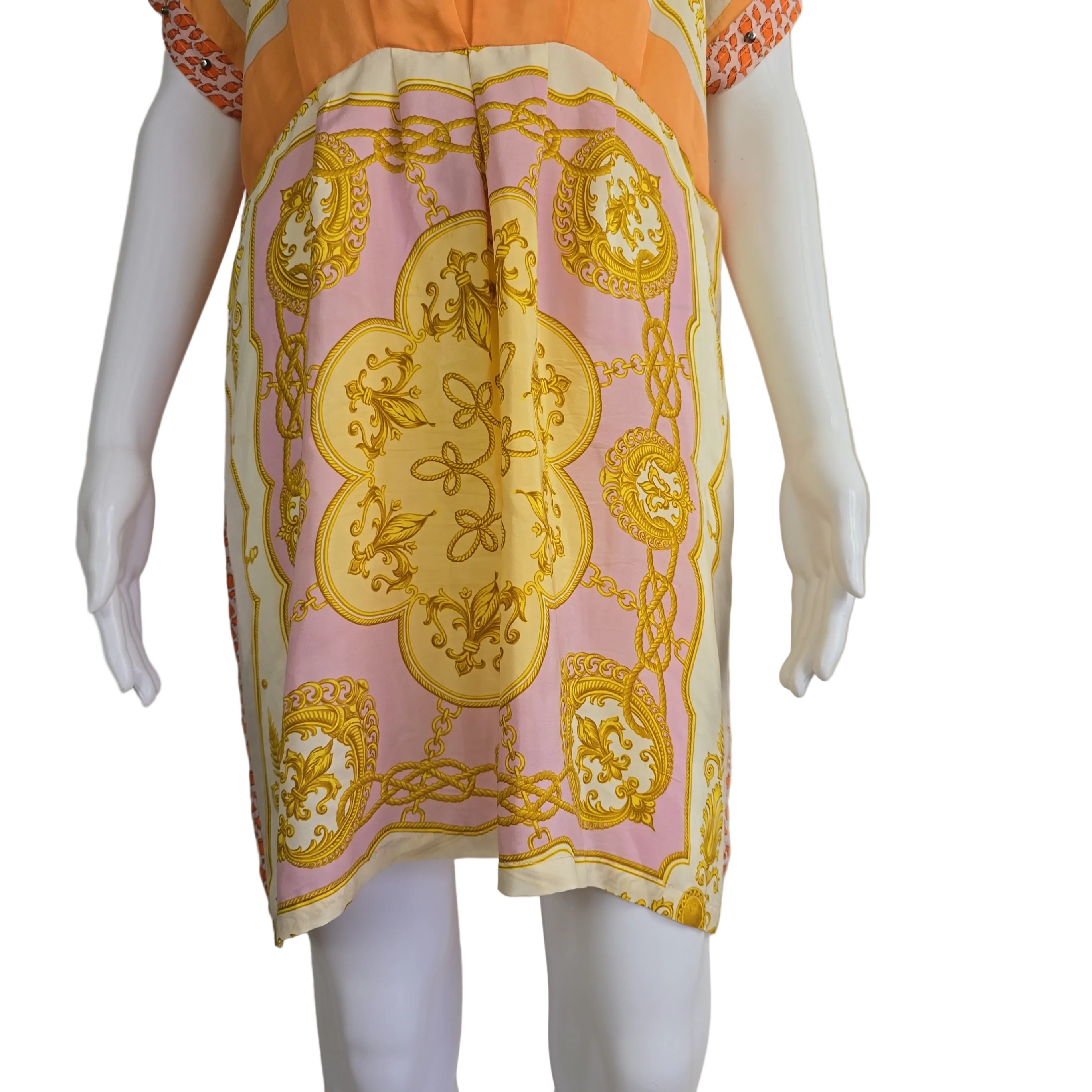 Mannequin wearing a dress with a pink and gold patterned kaftan against a beige background