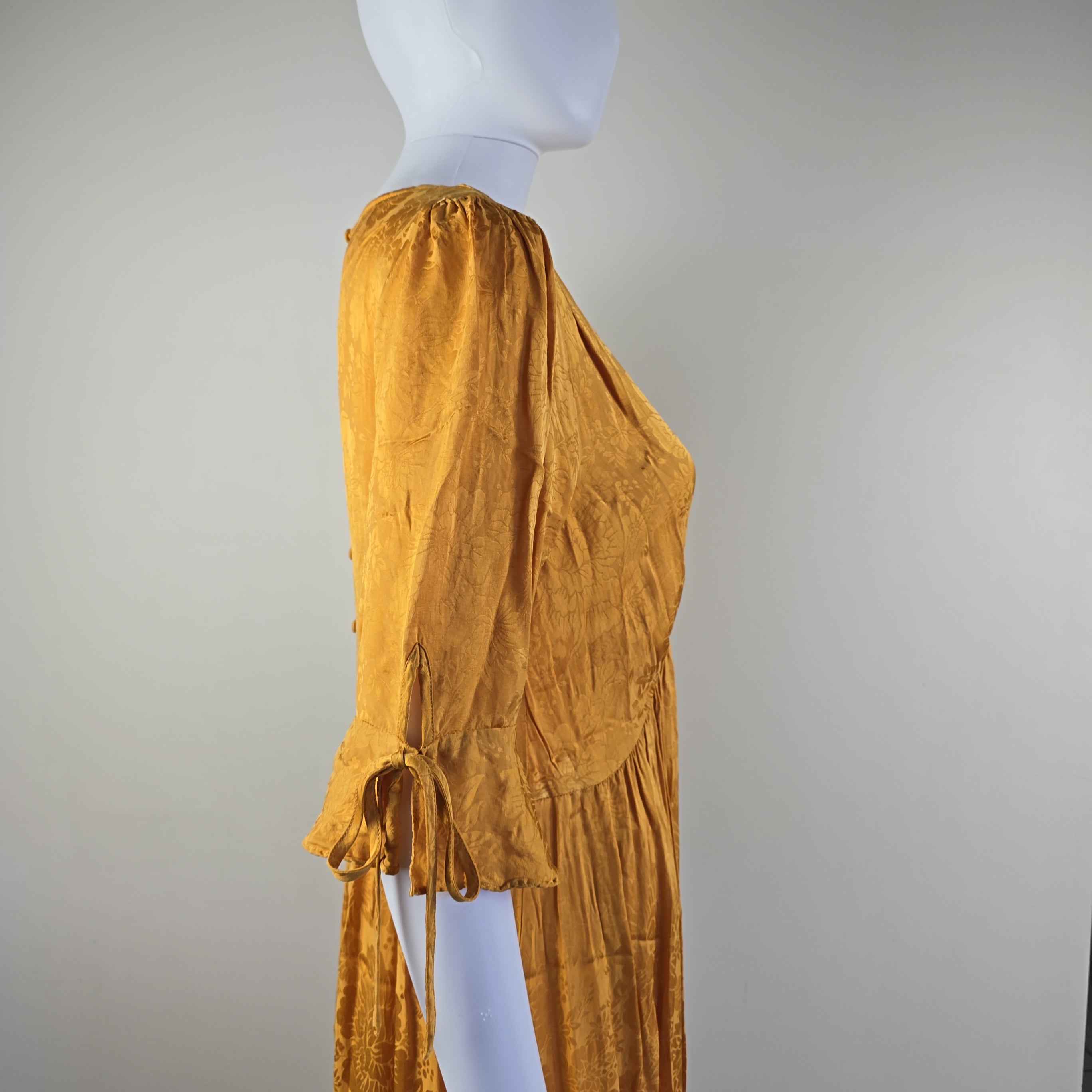Mustard yellow dress on a mannequin against a plain background