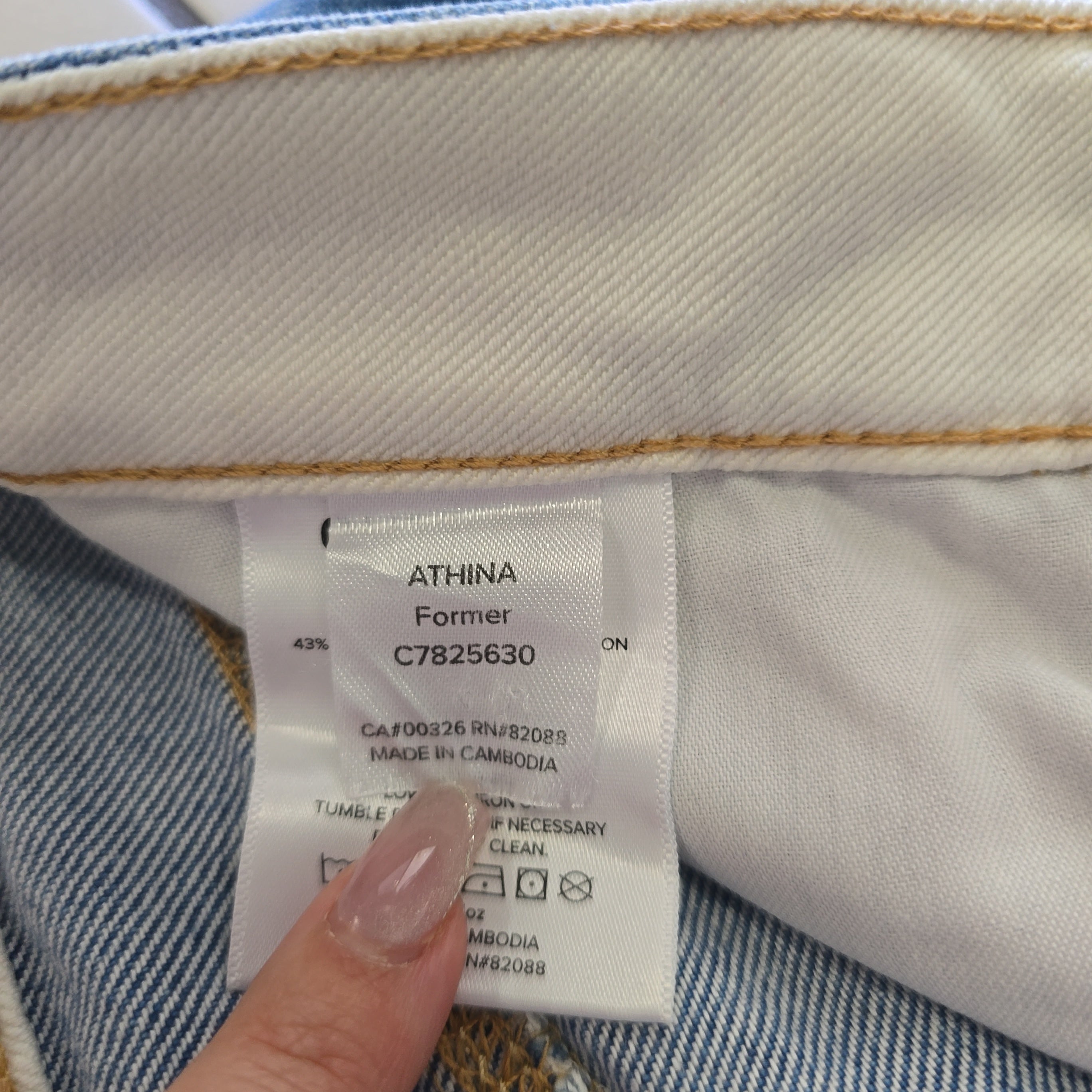 Close-up of a clothing label on denim fabric with a hand holding it.