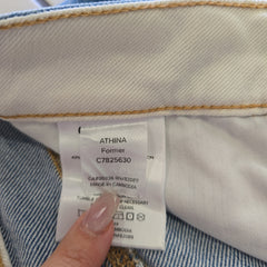 Close-up of a clothing label on denim fabric with a hand holding it.