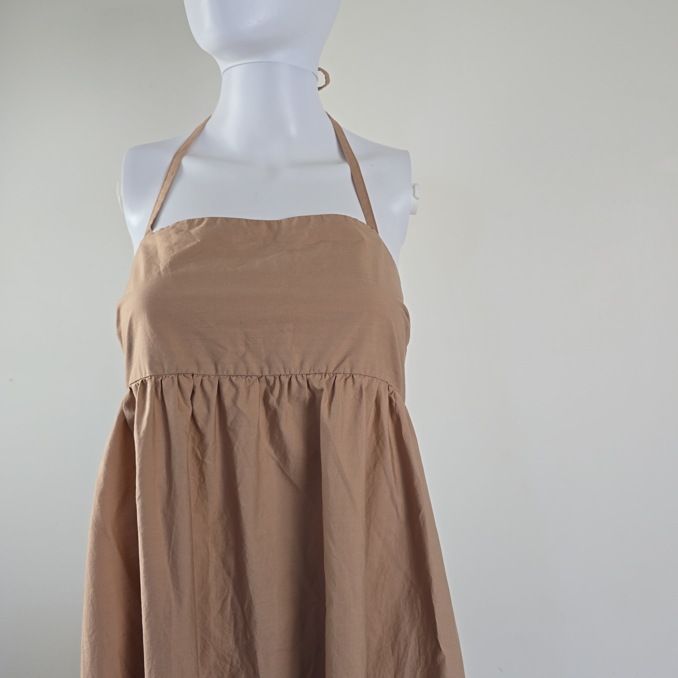 Mannequin wearing a beige dress against a plain background